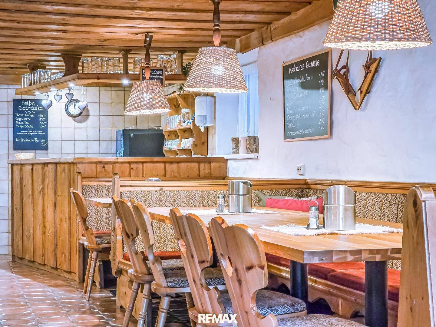 Gemütlicher Restaurantbereich mit Holztischen, Bänken und traditioneller Einrichtung.