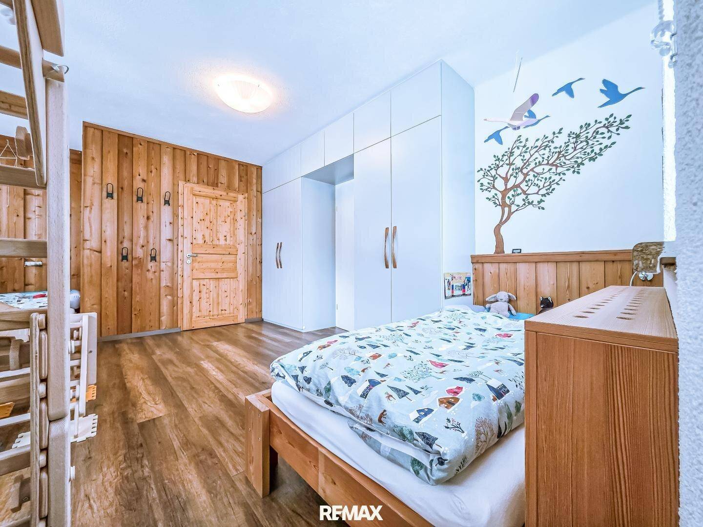 Kinderzimmer mit Holzwandverkleidung, Etagenbett und verspielter Wanddekoration, ideal für junge Bewohner.