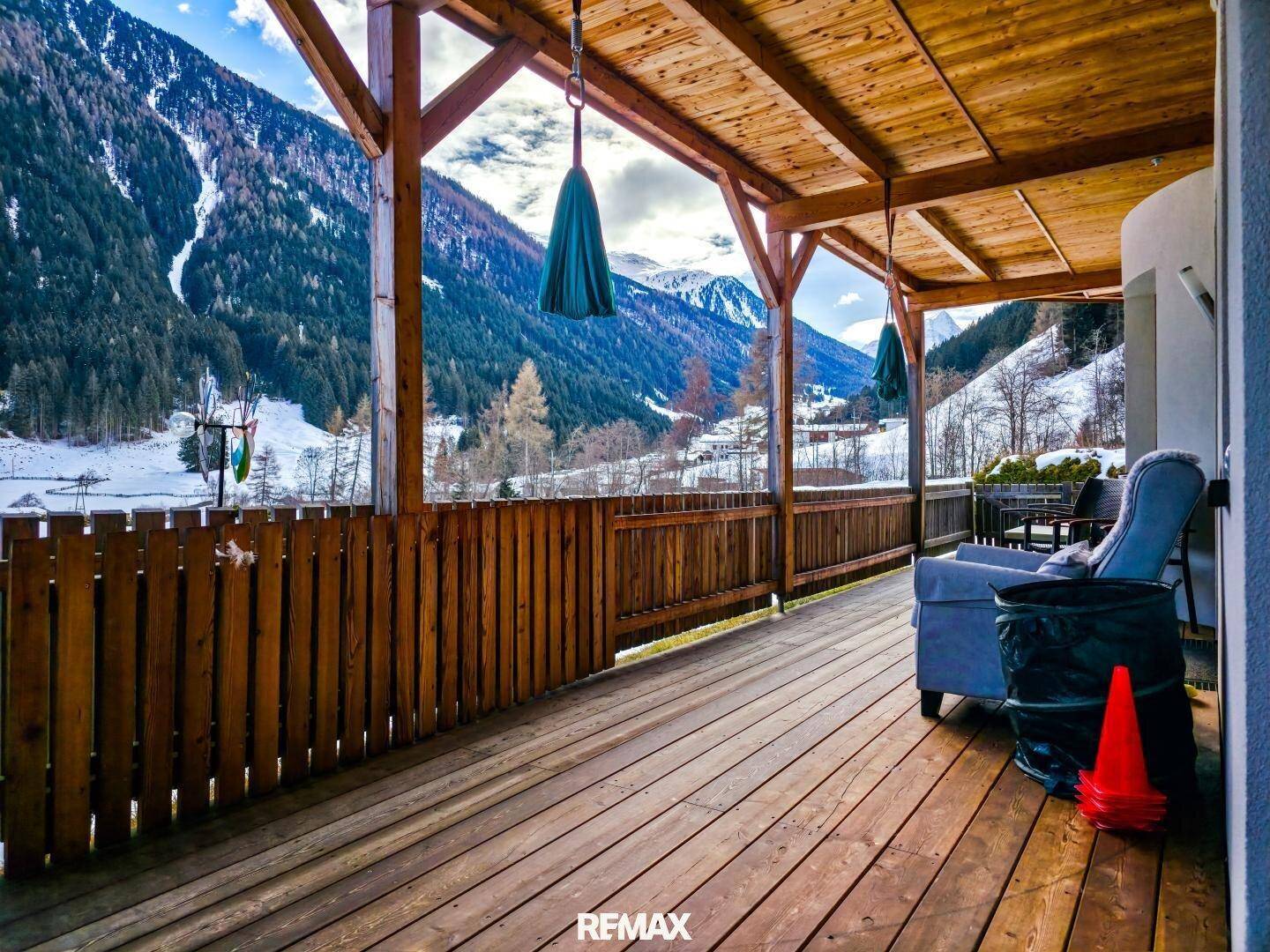 Überdachte Holzterrasse mit Sitzgelegenheiten und weitem Blick auf die umliegenden Berge.