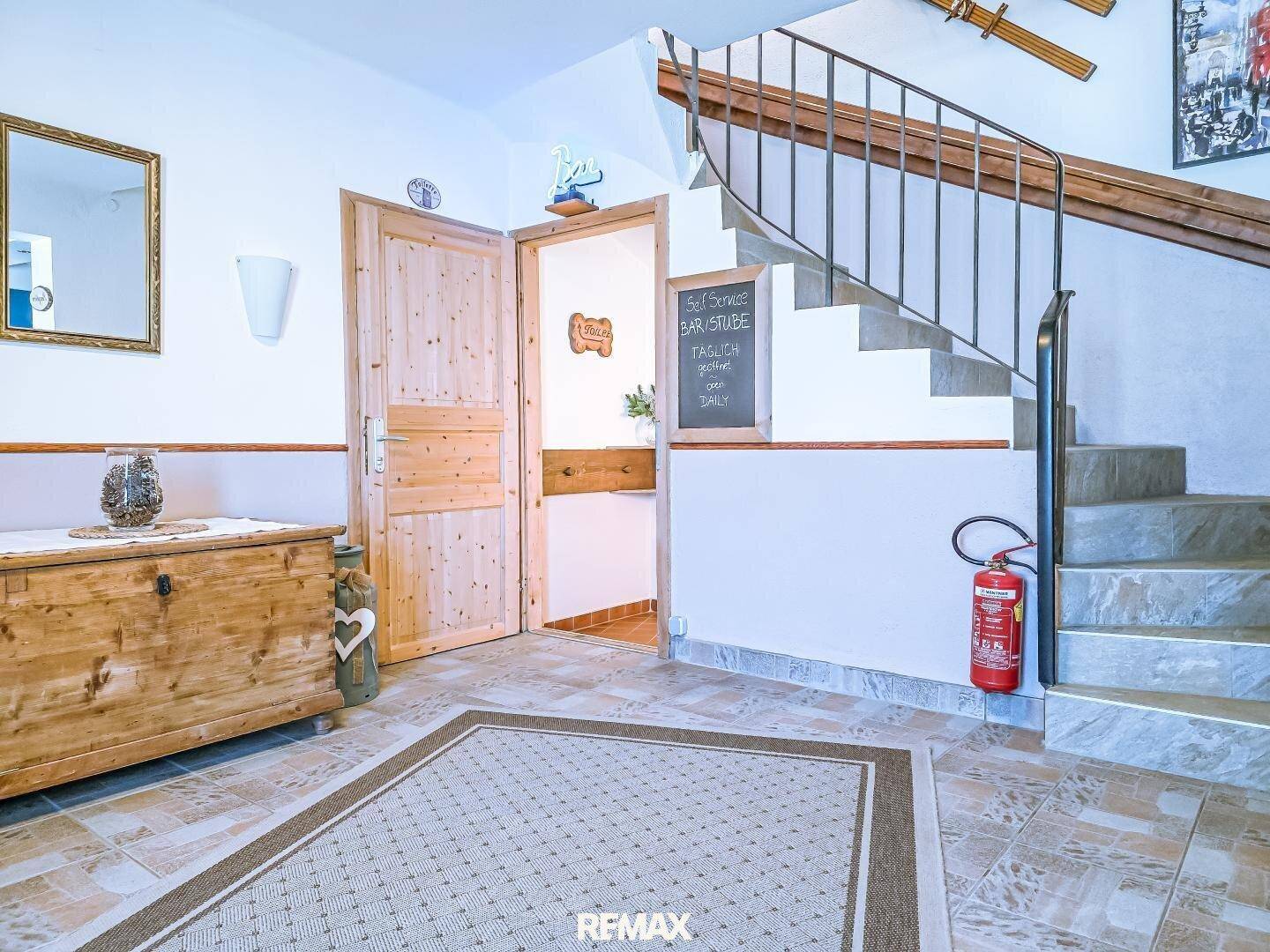 Eingangsbereich mit Steintreppe, Holztür und traditionellen Dekorationselementen.