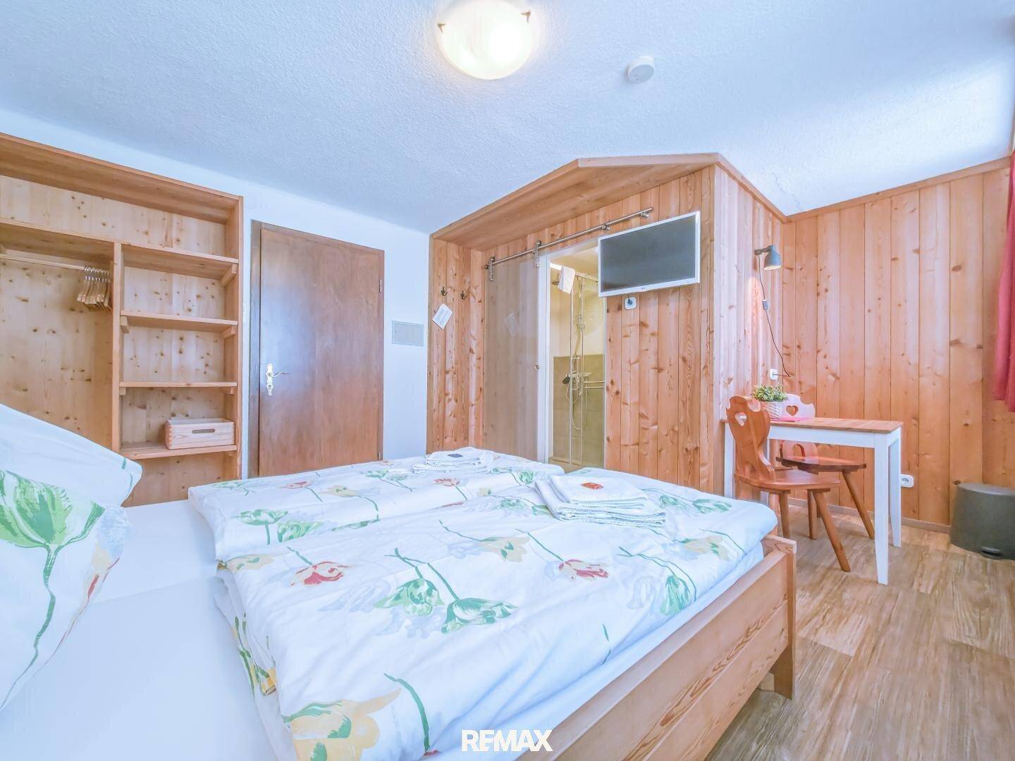Schlafzimmer mit Holzvertäfelung, Fernseher und direktem Zugang zu einem Badezimmer.