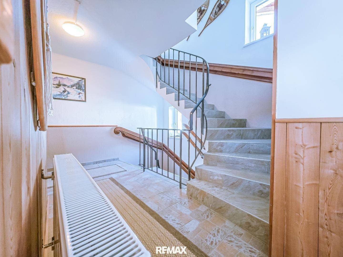 Elegantes Treppenhaus mit geschwungener Form, Steinstufen und schmiedeeisernem Geländer.