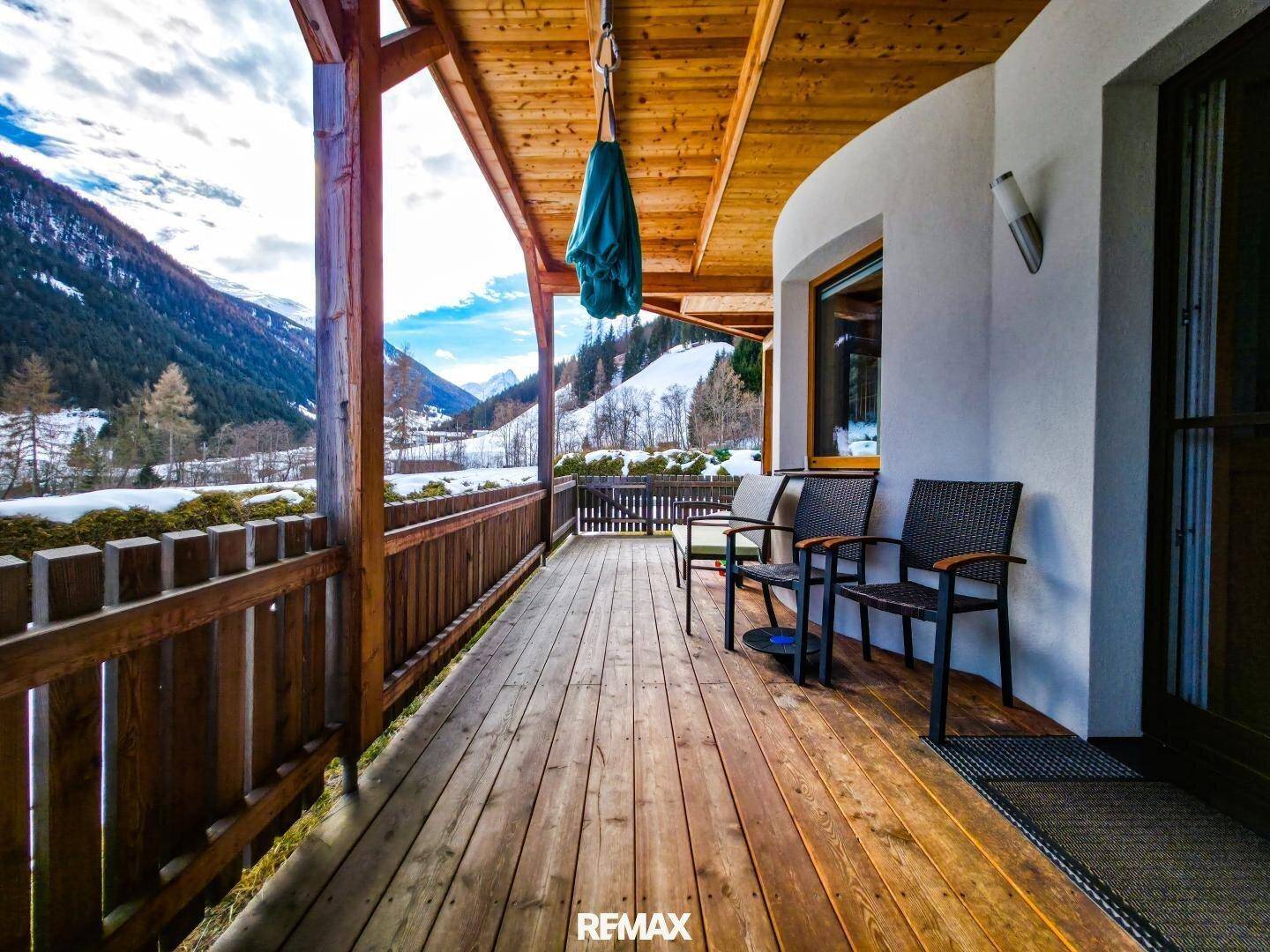 Geräumiger Balkon mit Holzboden und atemberaubendem Blick auf die schneebedeckten Berge und das Tal.
