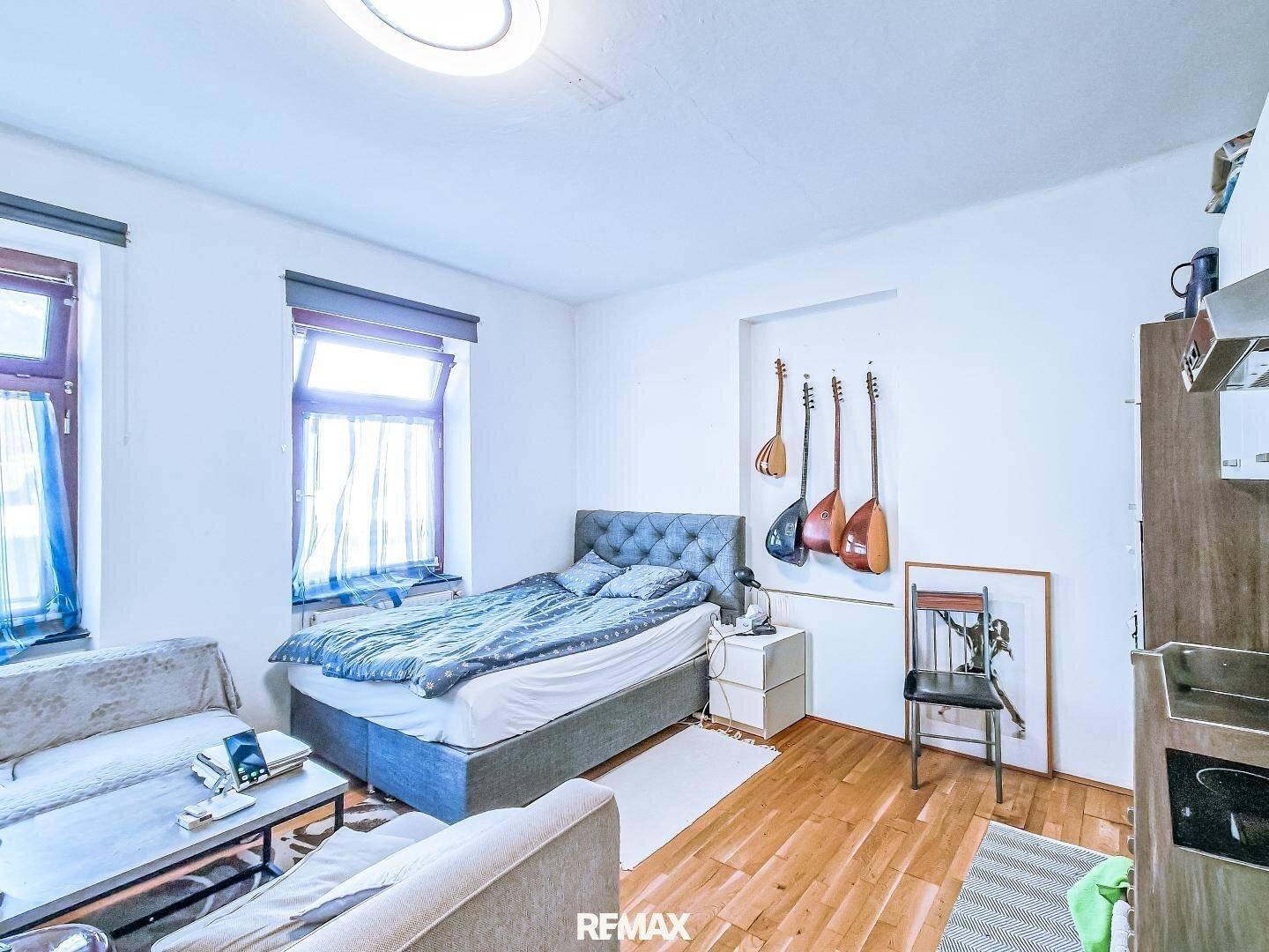Kombinierter Wohn- und Schlafbereich mit Bett, Sofa und Fenster für natürliches Licht.