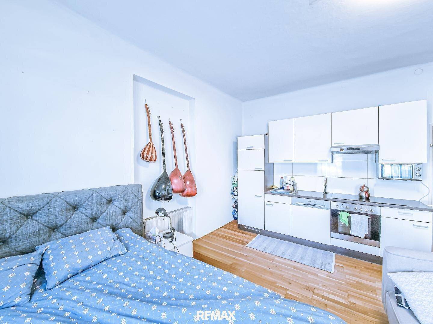 Heller Wohnbereich mit integrierter Küchenzeile und Schlafgelegenheit in einem Studio-Apartment.