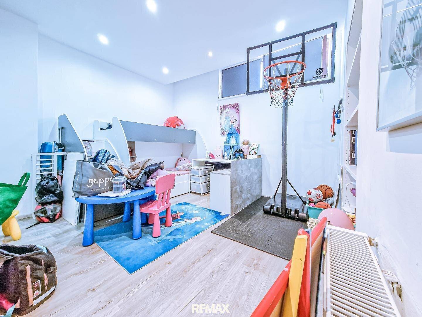 Kinderzimmer mit Etagenbett, Spielbereich und einem Basketballkorb für sportliche Aktivitäten.
