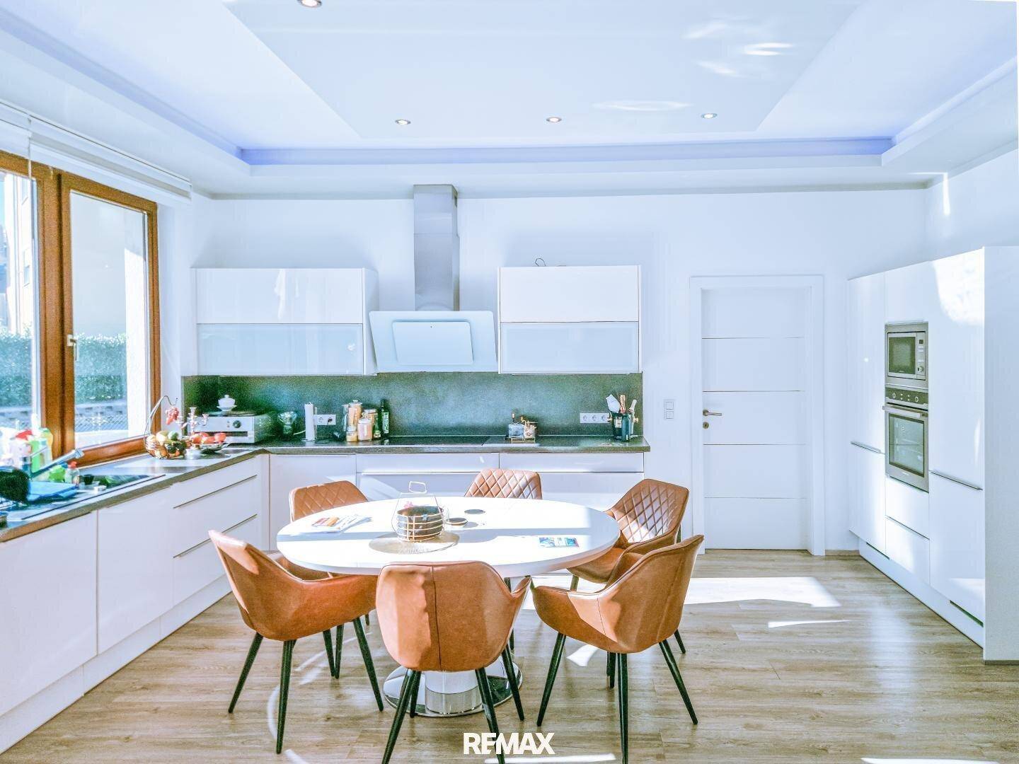 Moderne Einbauküche mit Essbereich, integriertem Backofen und Mikrowelle.