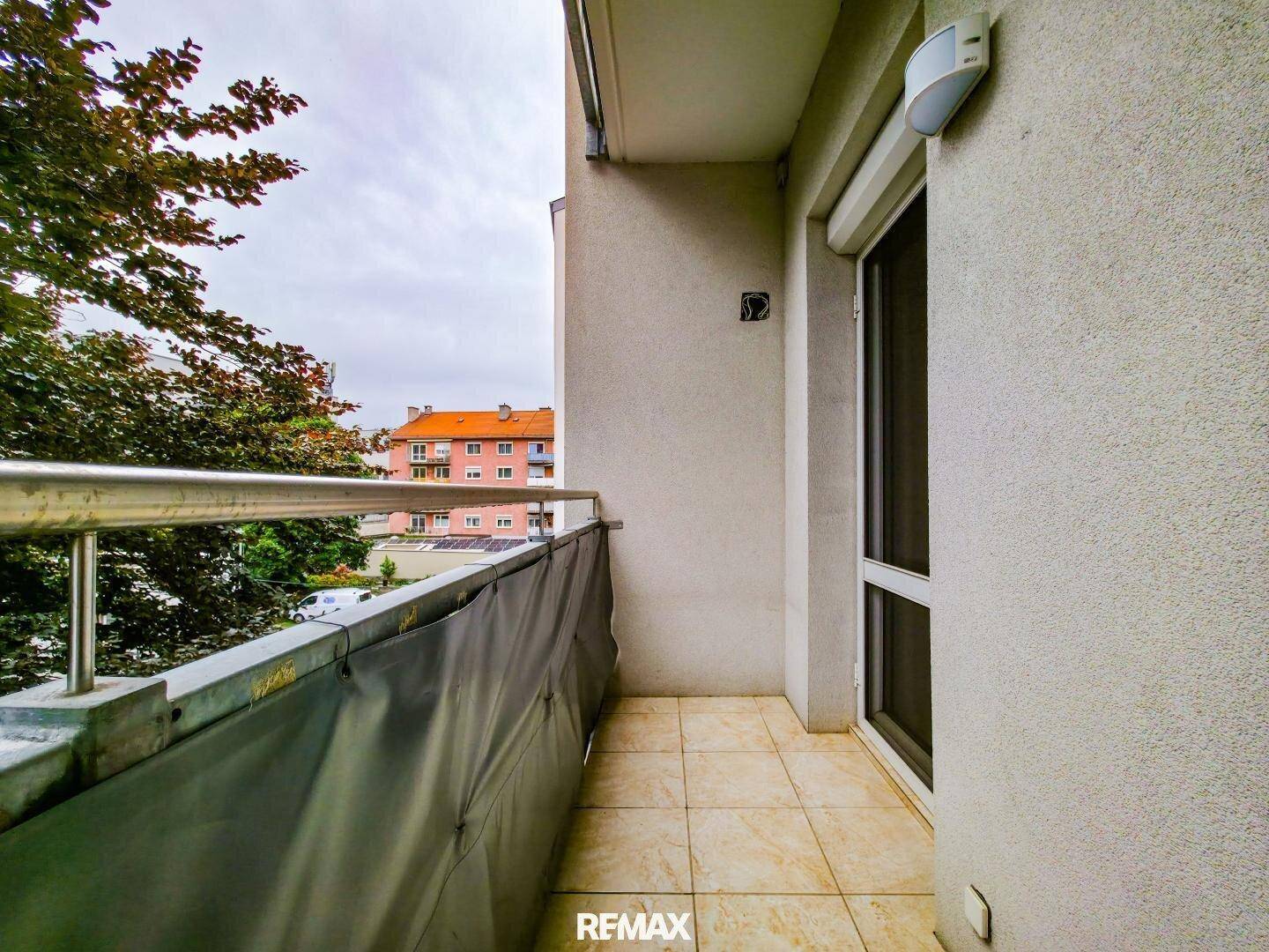 Kleiner Balkon mit Fliesenboden und Blick auf die Umgebung.
