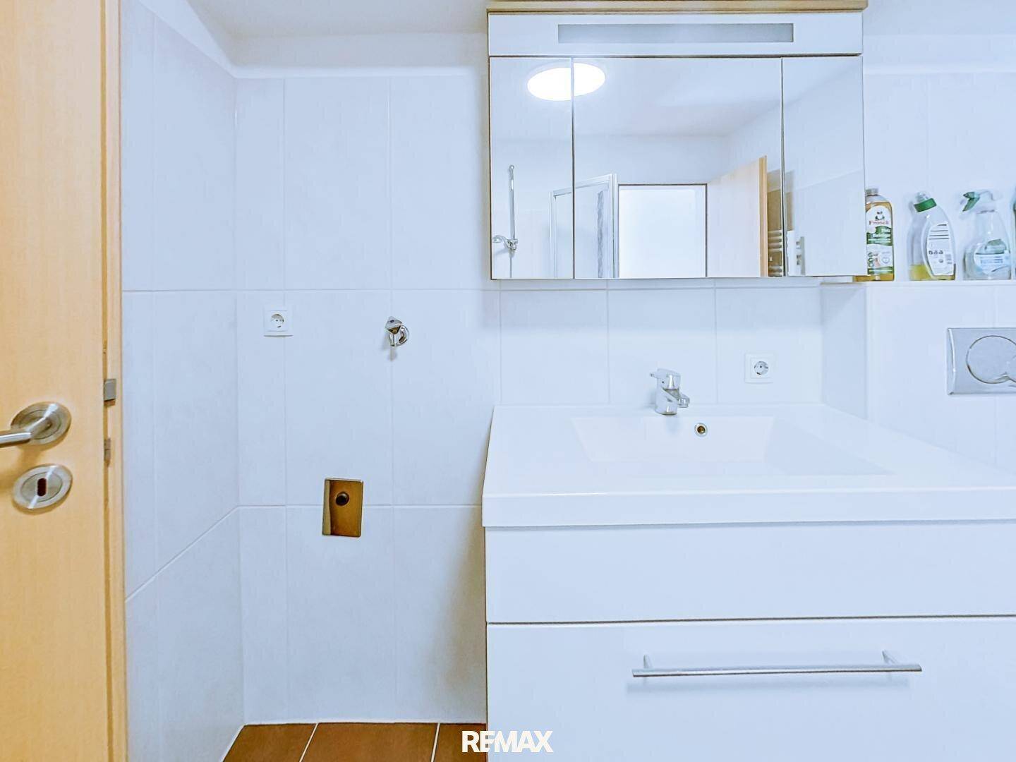 Badezimmer mit modernem Waschbeckenunterschrank und Spiegelschrank über dem Waschbecken.