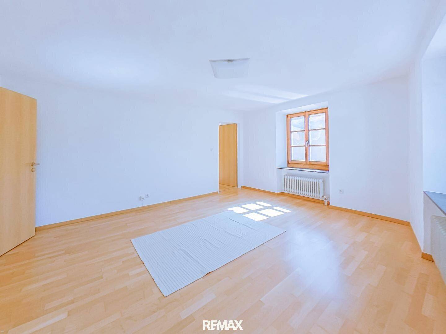 Geräumiges, helles Zimmer mit Parkettboden und Holzfenstern, ideal als Wohnbereich.