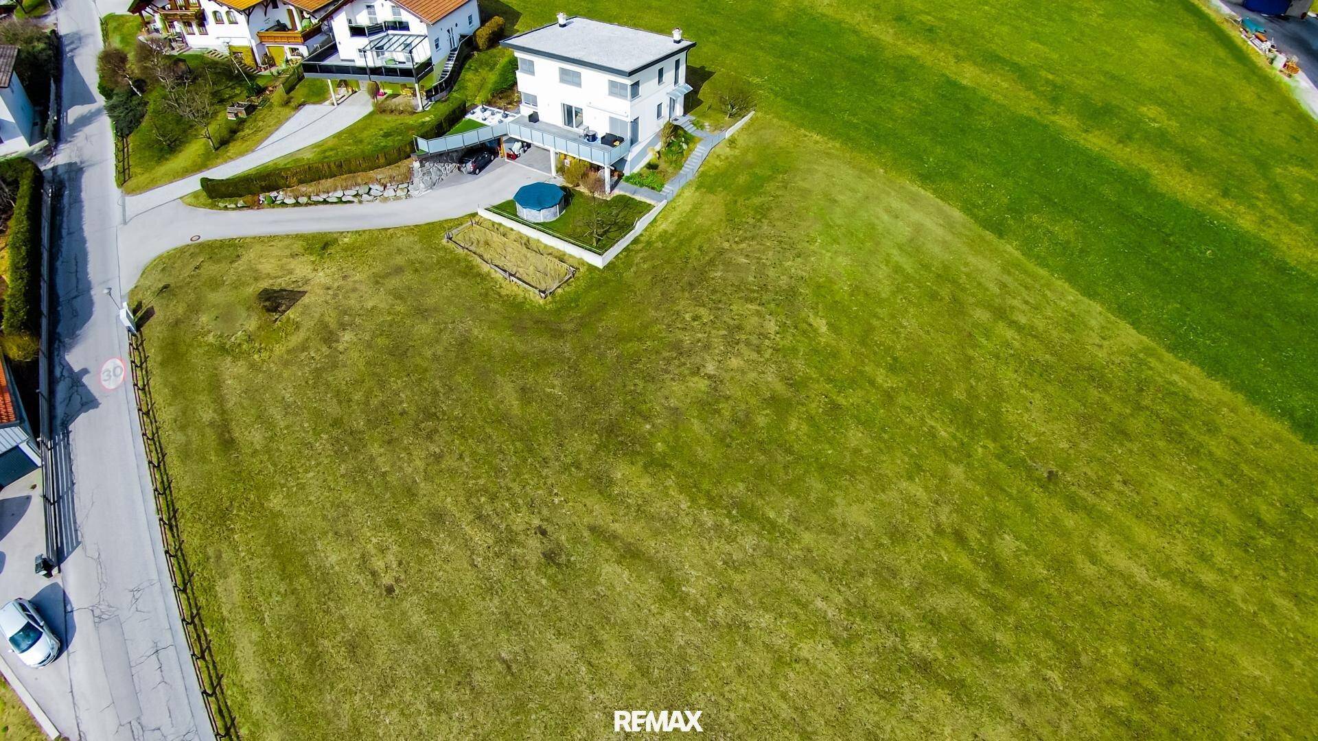 Luftaufnahme eines modernen Hauses mit Flachdach, kleinem Pool und weitläufiger grüner Rasenfläche.