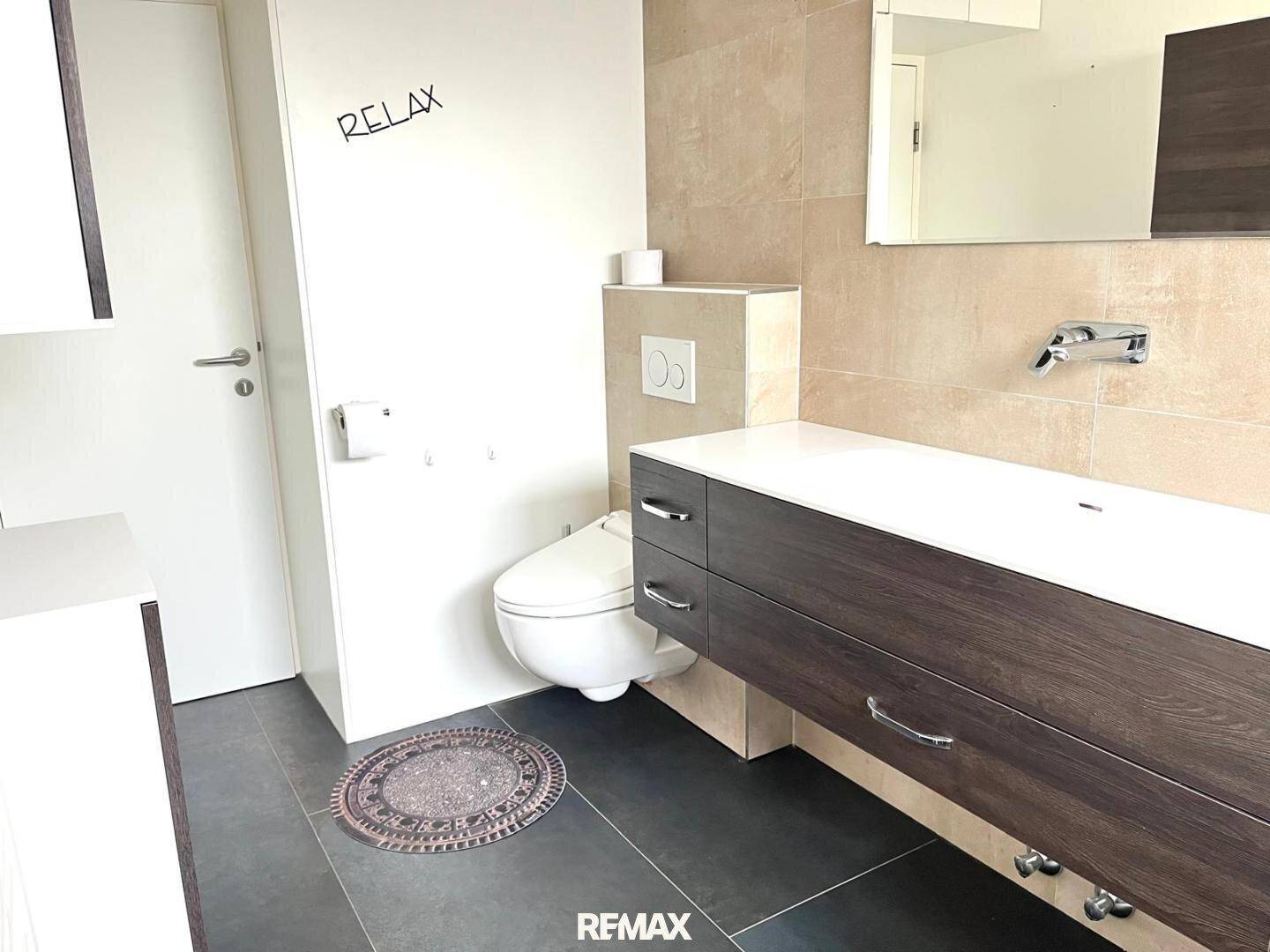 Helles Badezimmer mit modernem Waschtisch, wandhängendem WC und großen Fliesen.