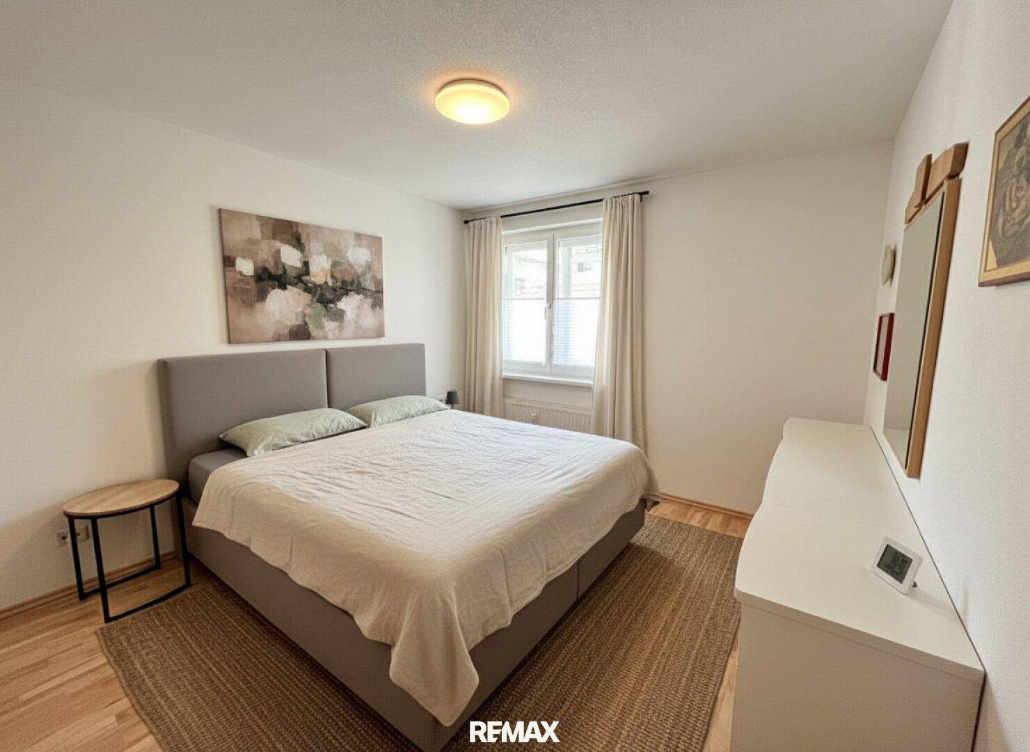 Gemütliches Schlafzimmer mit großem Doppelbett, Holzboden und einem Fenster für Tageslicht.
