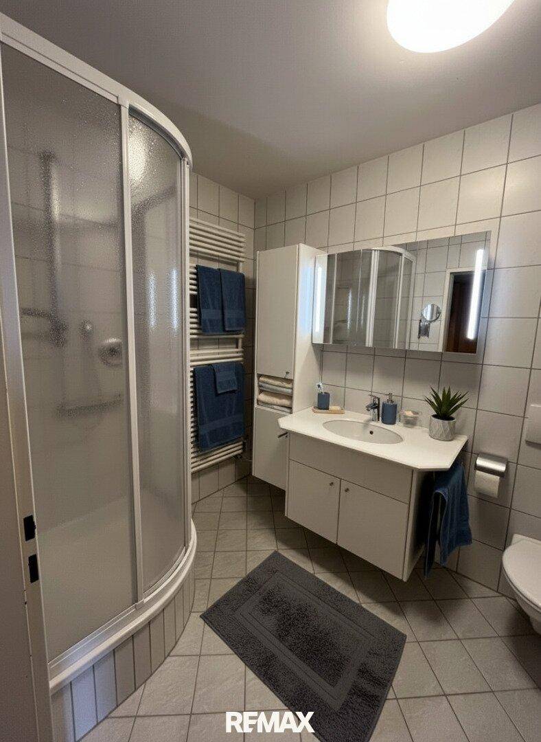 Modernes Badezimmer mit Duschkabine, Einzelwaschbecken und beheiztem Handtuchhalter.