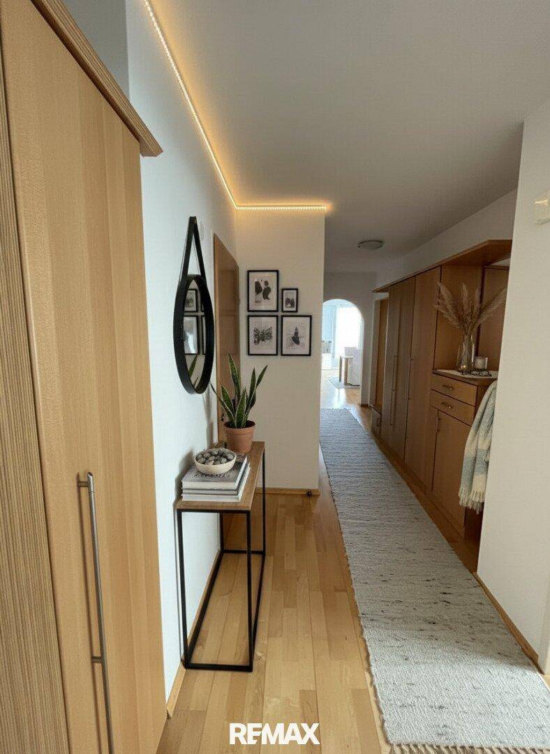 Heller Flur mit Holzschränken, indirekter Beleuchtung und modernem Spiegeldesign.