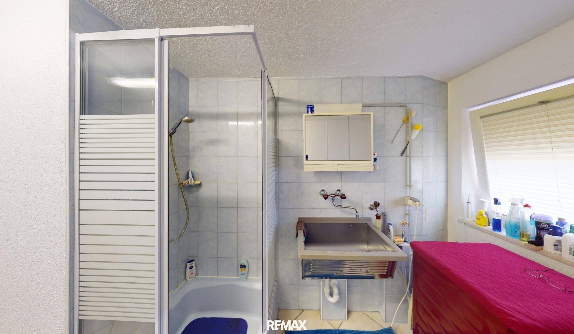 Hauswirtschaftsraum mit Duschkabine, großem Waschbecken und Fenster.