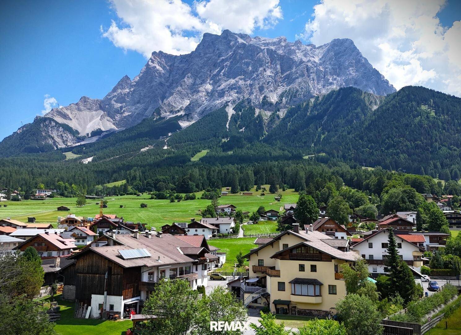 Panoramablick auf ein malerisches Dorf vor der Kulisse majestätischer Berge und grüner Täler.