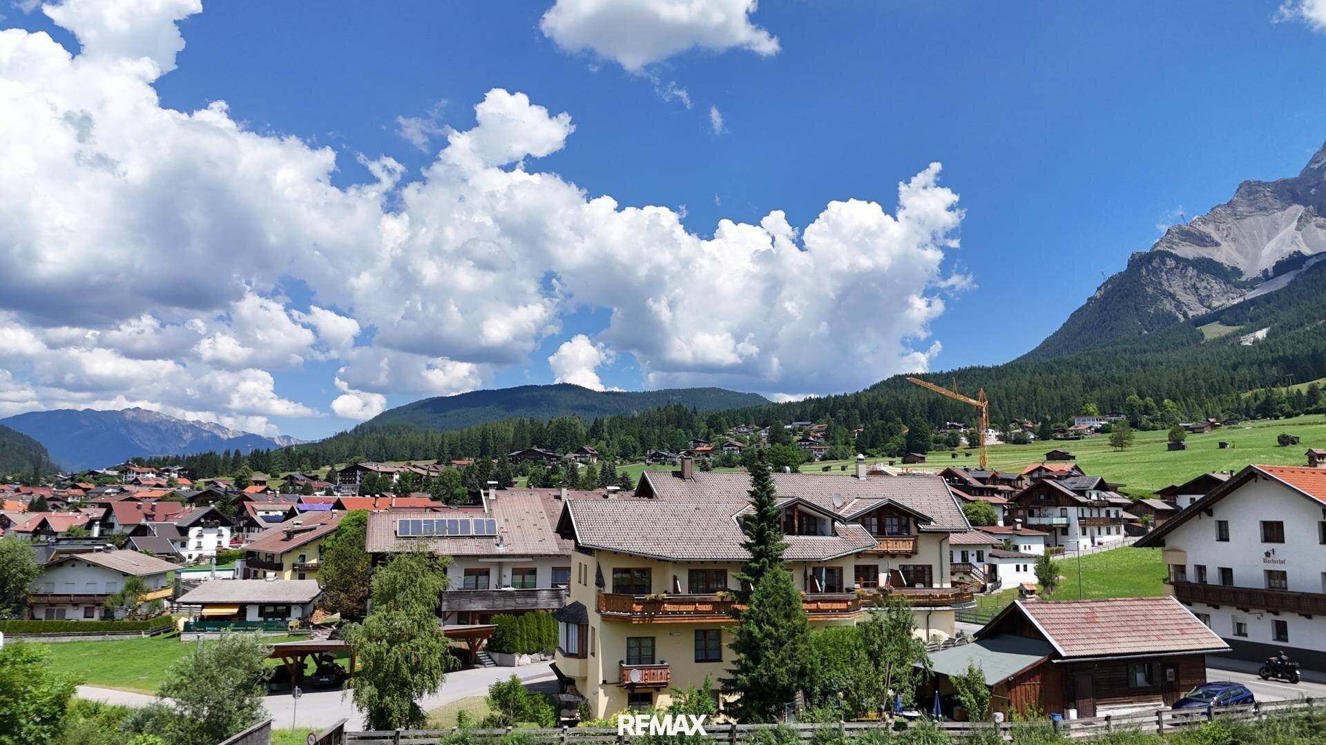 Weitläufige Ansicht eines Dorfes in den Bergen mit traditionellen Häusern und viel Grün.