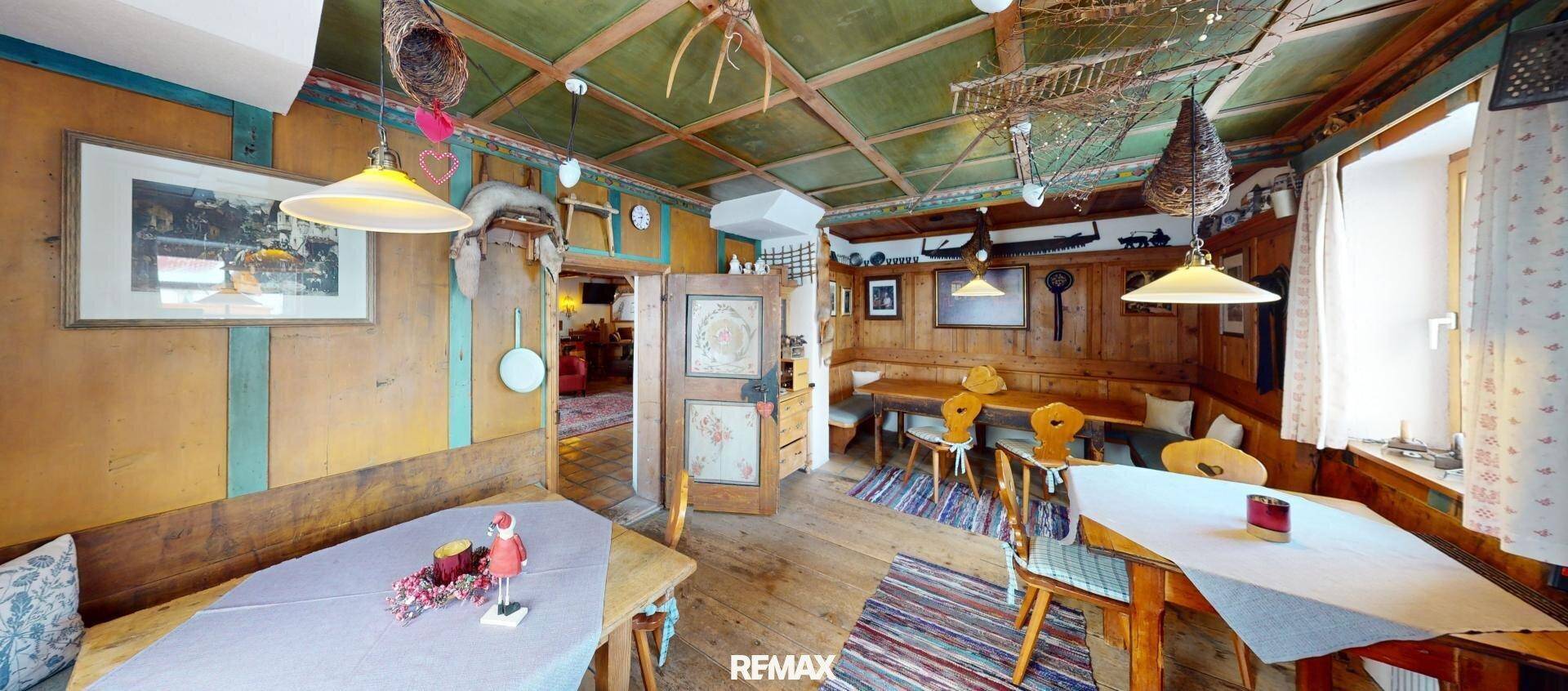 Rustikaler Essbereich mit Holztischen, Bänken und einer farbenfrohen Holzdecke im Landhausstil.
