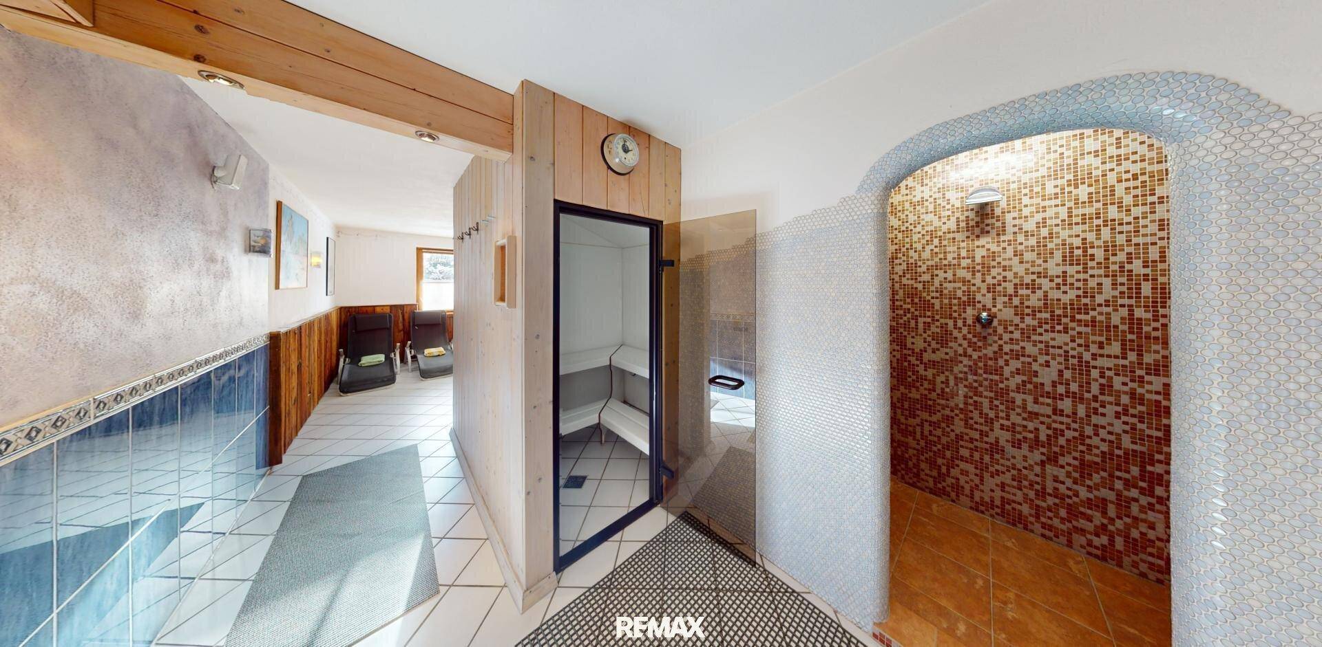 Wellnessbereich mit Sauna, Duschkabine und Liegestühlen, ausgestattet mit Mosaikfliesen.