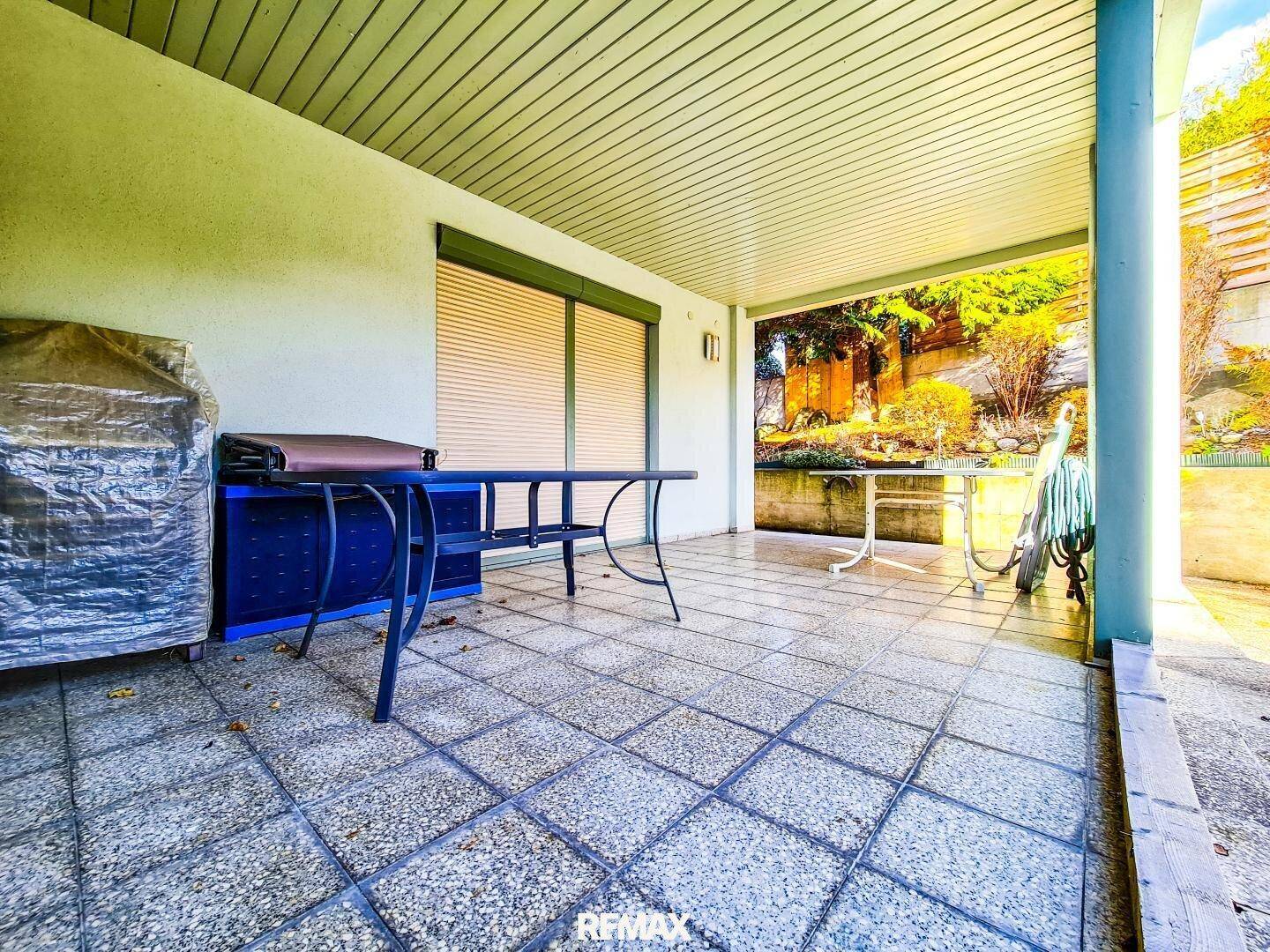 Überdachte Terrasse mit Fliesenboden und Gartenblick, ideal für entspannte Stunden im Freien.