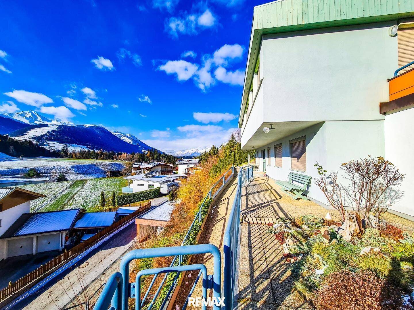 Langer Balkon entlang des Hauses mit Geländer und Blick auf die verschneite Landschaft und Berge.