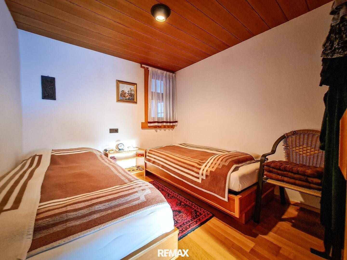 Gemütliches Schlafzimmer mit zwei Einzelbetten, Holzdecke und Parkettboden, gut gepflegt.