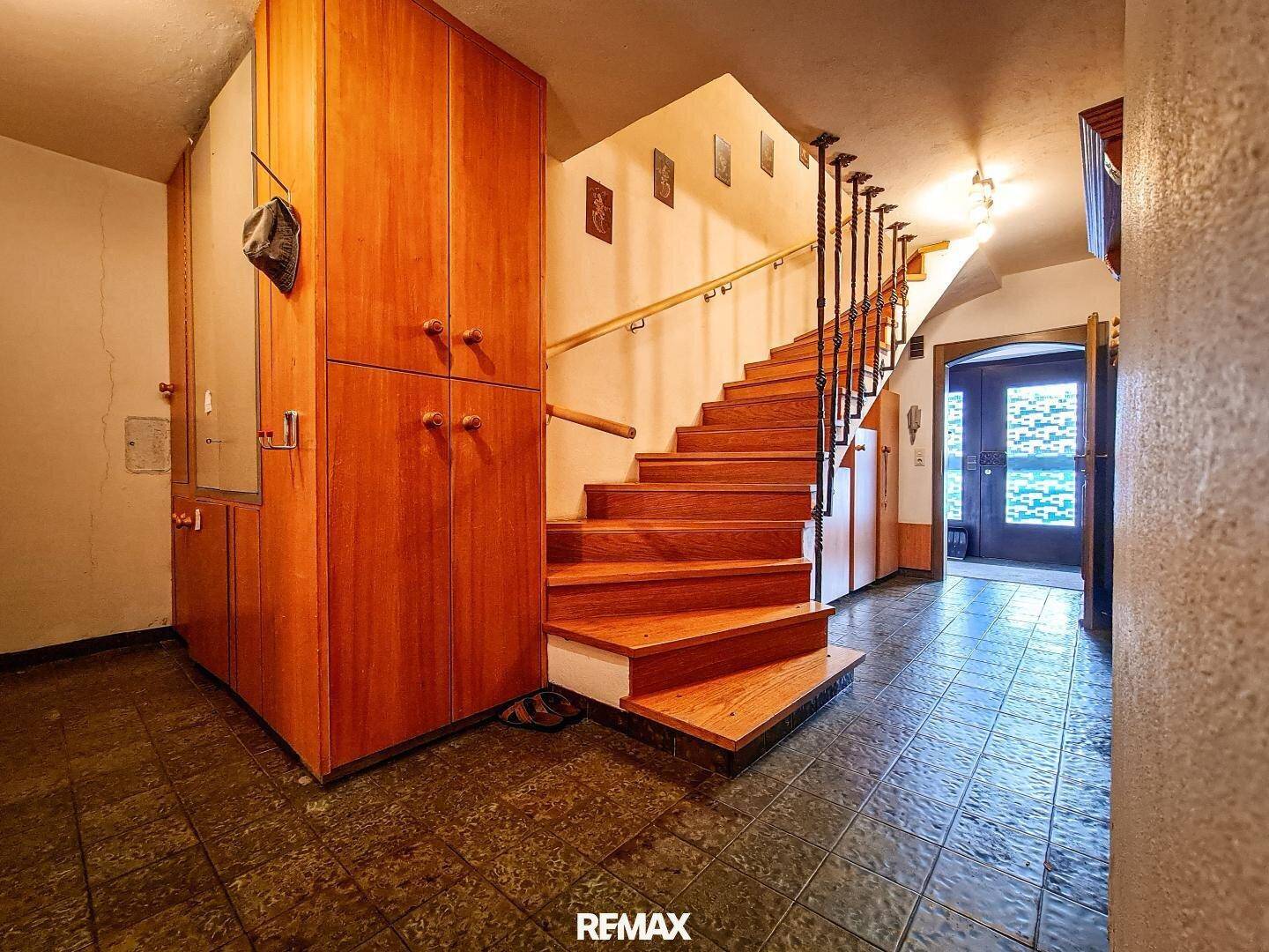 Geräumiger Eingangsbereich mit Holztreppe, Einbauschränken und gefliestem Boden im traditionellen Stil.