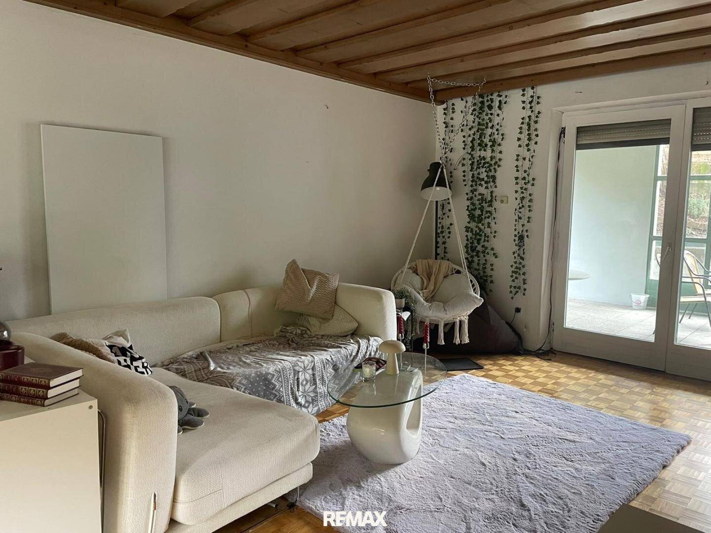 Helles Wohnzimmer mit Parkettboden, bequemer Couch und Zugang zur Terrasse.