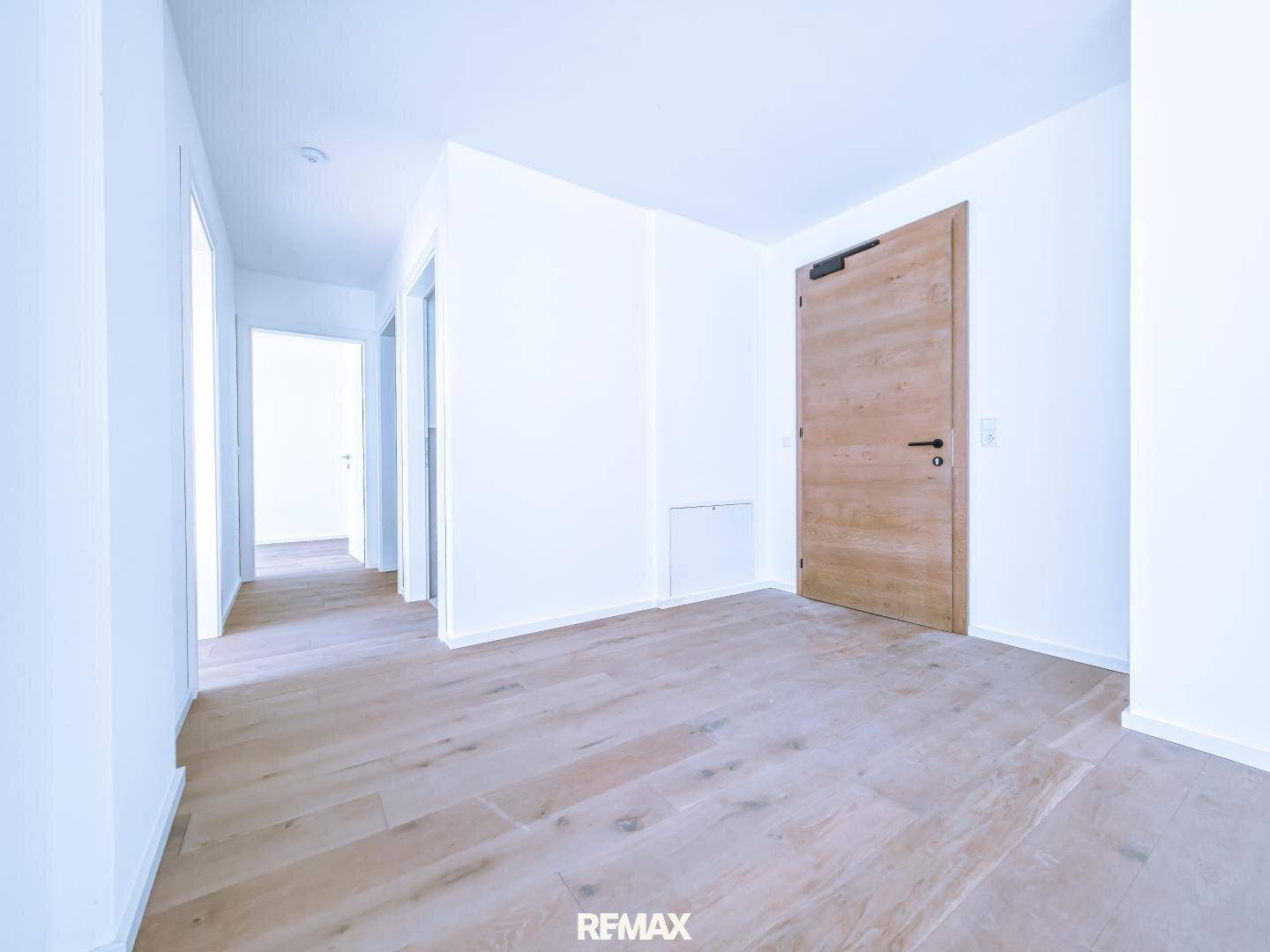 Heller Flurbereich mit Holzboden und modernen Holztüren, der zu weiteren Räumen führt.
