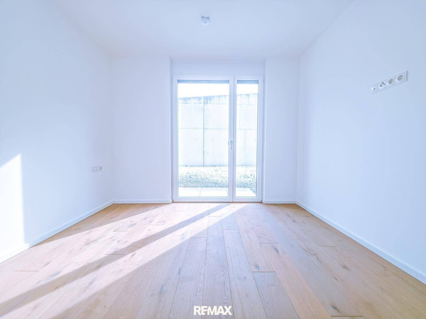 Helles Schlafzimmer mit Holzboden und Zugang zu einem Außenbereich, ideal für Ruhe.