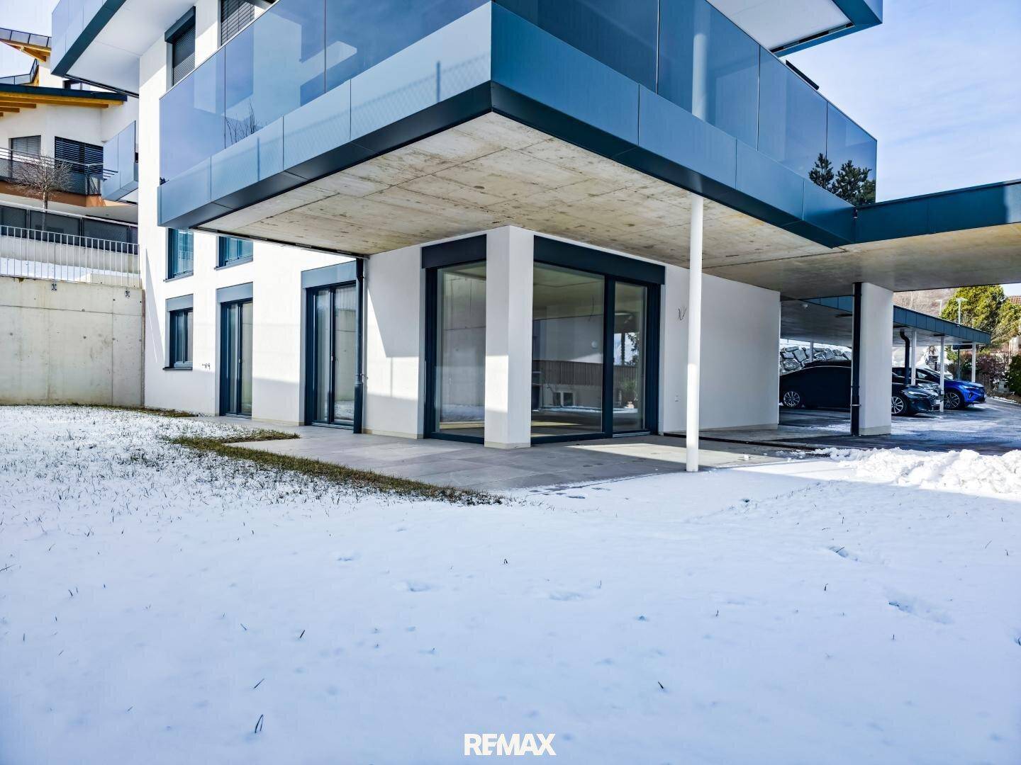 Erdgeschoss einer modernen Wohnanlage mit großen Fenstern und schneebedecktem Vorgartenbereich.