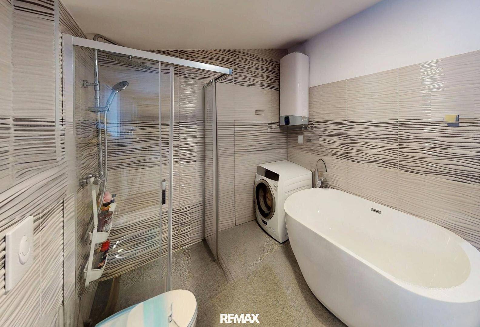 Modernes Badezimmer mit freistehender Badewanne, Duschkabine und Waschmaschine.