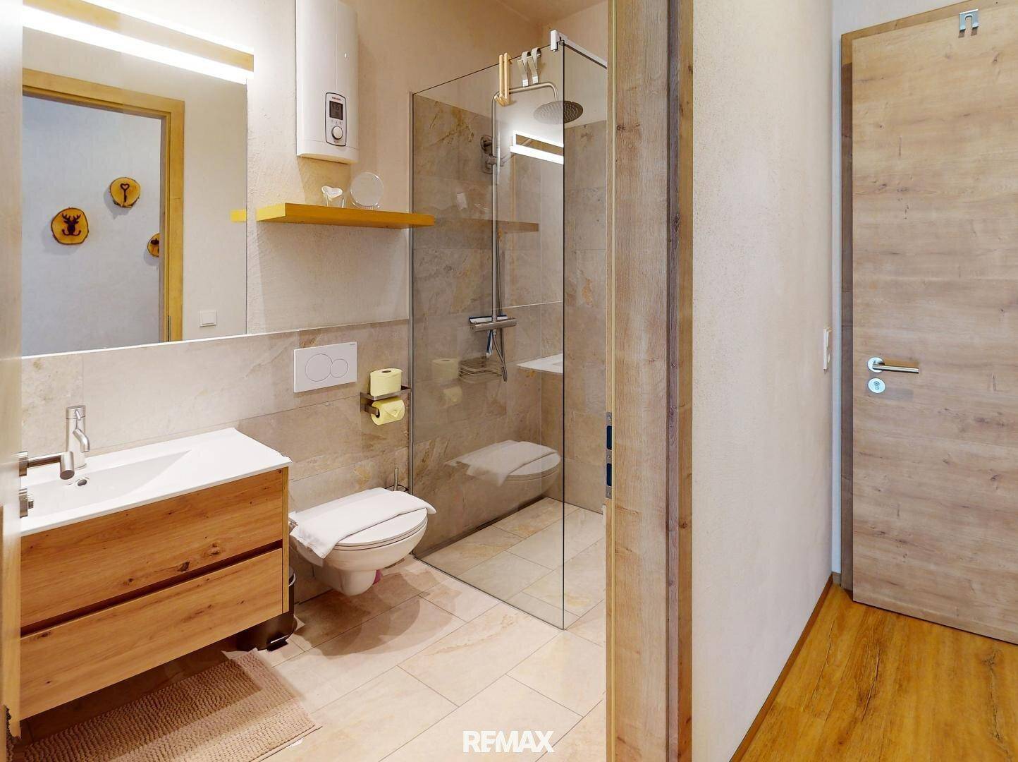 Modernes Badezimmer mit ebenerdiger Dusche, Wand-WC und Holzwaschtisch.