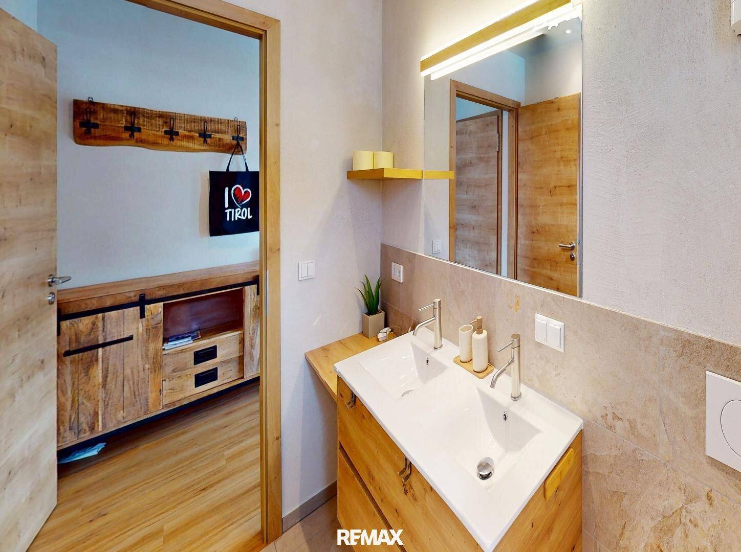 Modernes Badezimmer mit Doppelwaschbecken, Holzunterschrank und großem Spiegel.