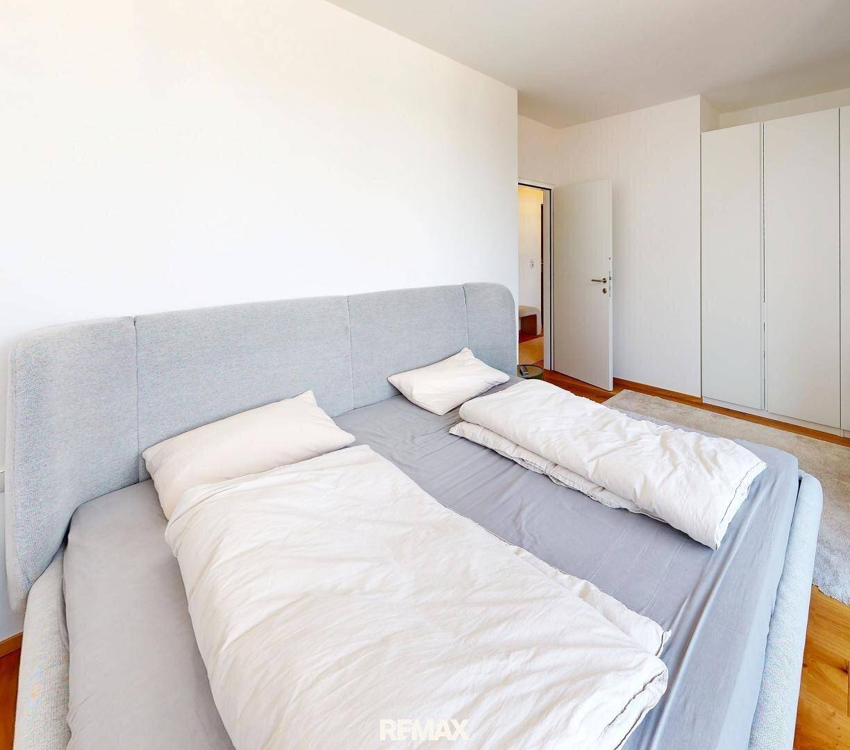 Geräumiges Schlafzimmer mit großem Doppelbett, hellem Teppich und praktischen Einbauschränken.