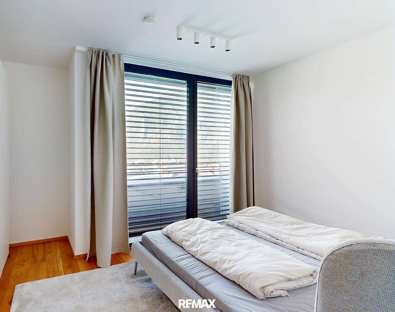 Schlafzimmer mit Doppelbett und direktem Zugang zu einem Balkon, der viel Tageslicht hereinlässt.