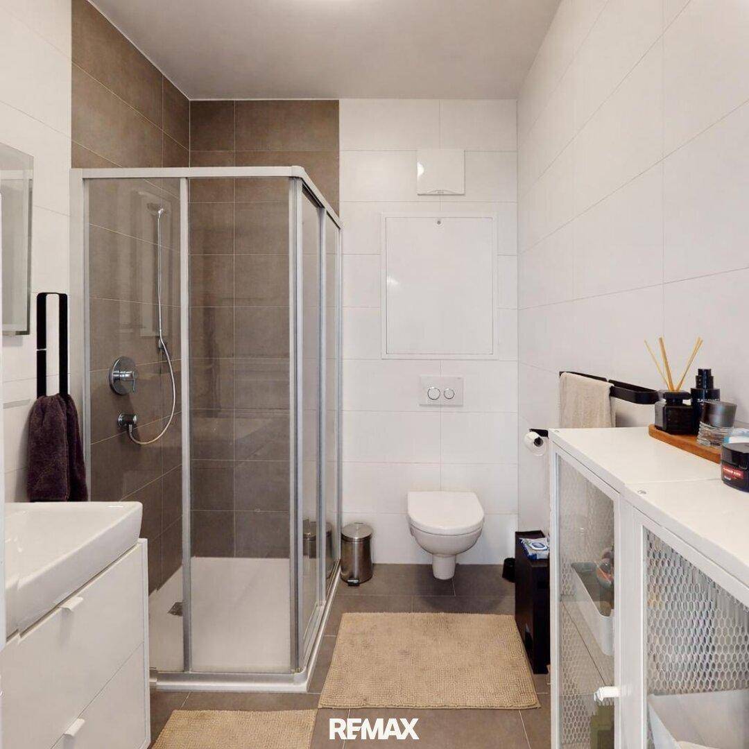 Modernes Badezimmer mit Duschkabine, wandhängendem WC und Waschbecken mit Unterschrank.