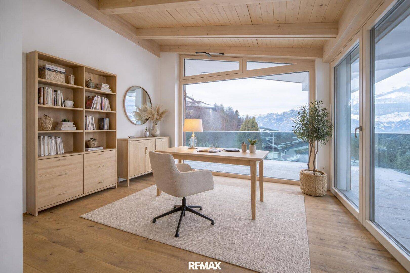 Modernes Büro mit Holzboden, Holzbalkendecke und großem Fenster mit inspirierendem Bergblick.