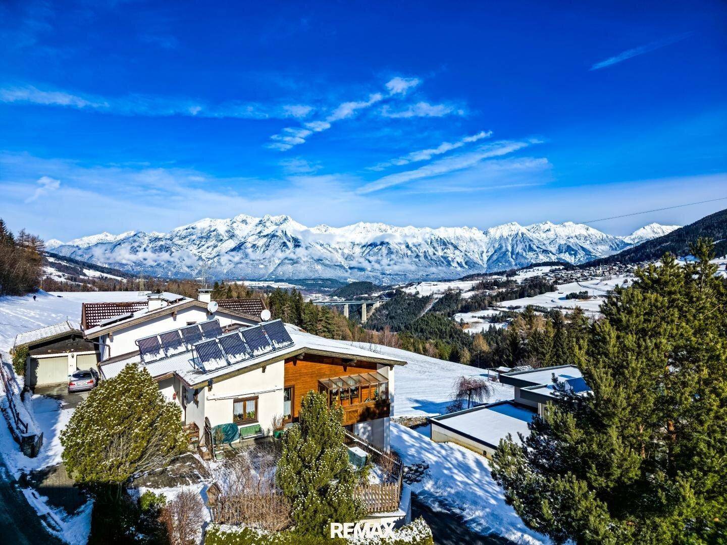 Malerisches Dorf in einer verschneiten Berglandschaft mit traditionellen Häusern und weitem Blick.