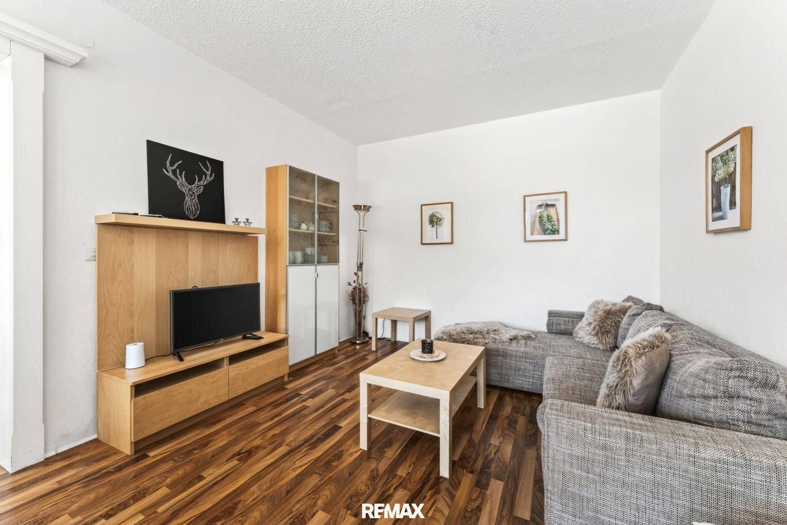 Geräumiges Wohnzimmer mit TV-Möbeln aus Holz, bequemer Couch und Parkettboden.