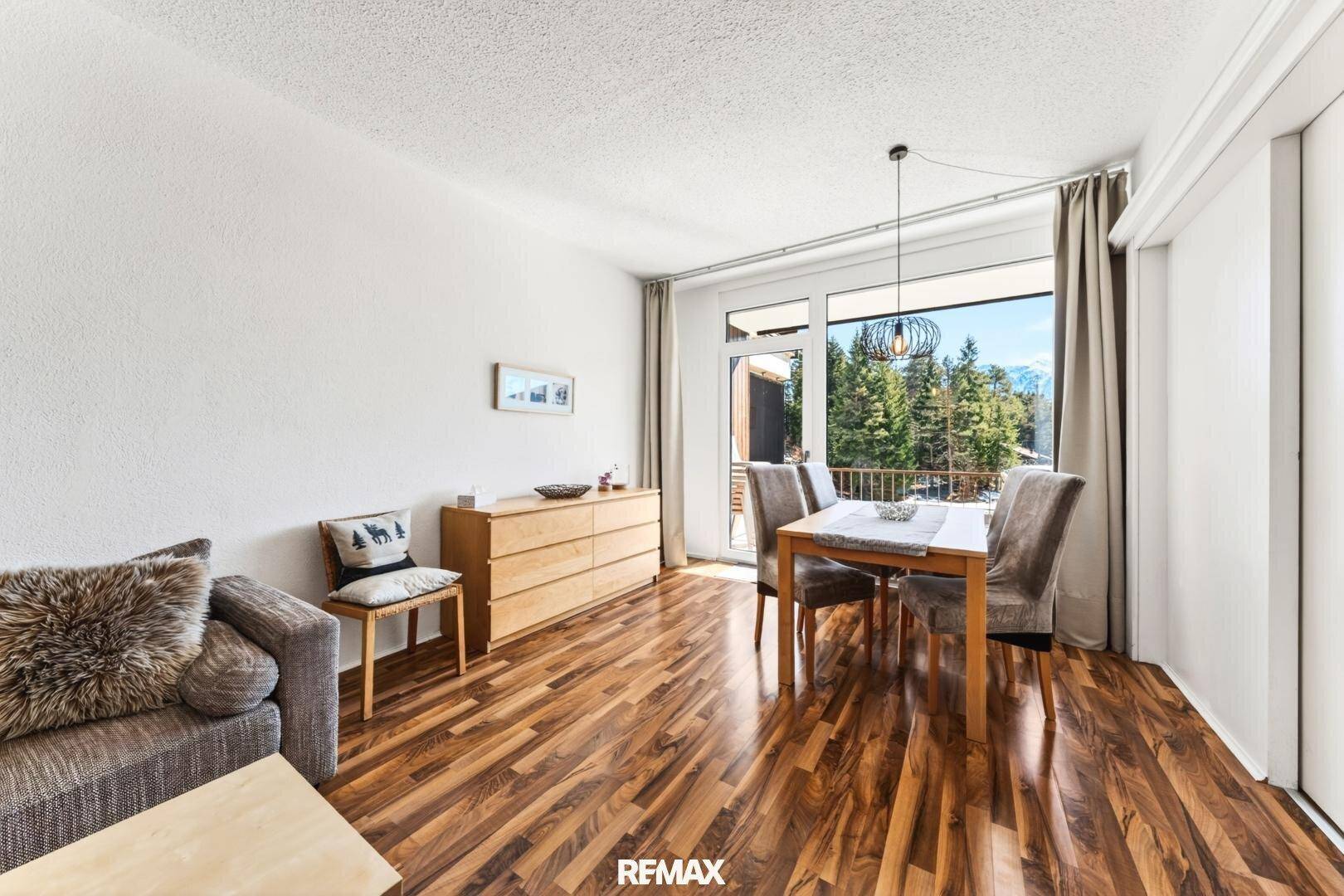 Offener Wohn- und Essbereich mit bequemer Couch, Holzboden und Zugang zum Außenbereich.