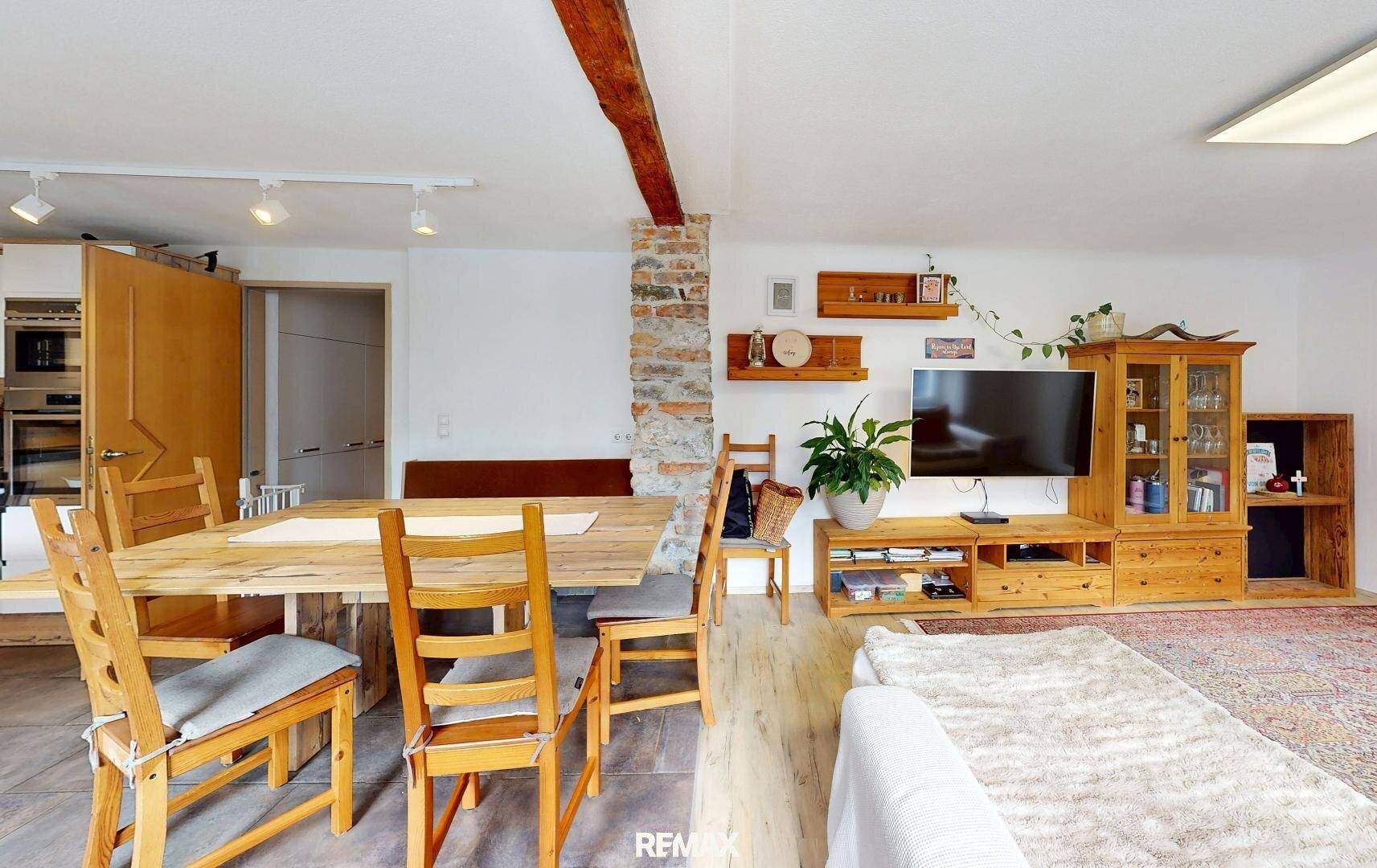 Geräumiger Essbereich mit großem Holztisch und Stühlen, angrenzend an den Wohnbereich mit TV.