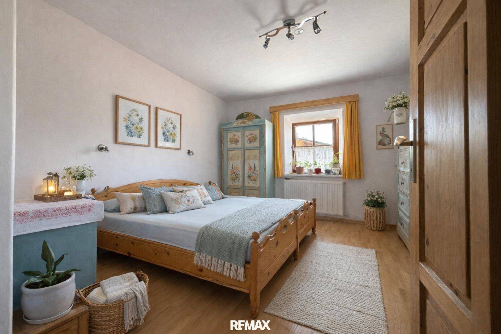 Helles Schlafzimmer mit Holzbett, floralem Kleiderschrank und Holzboden im gemütlichen Landhausstil.
