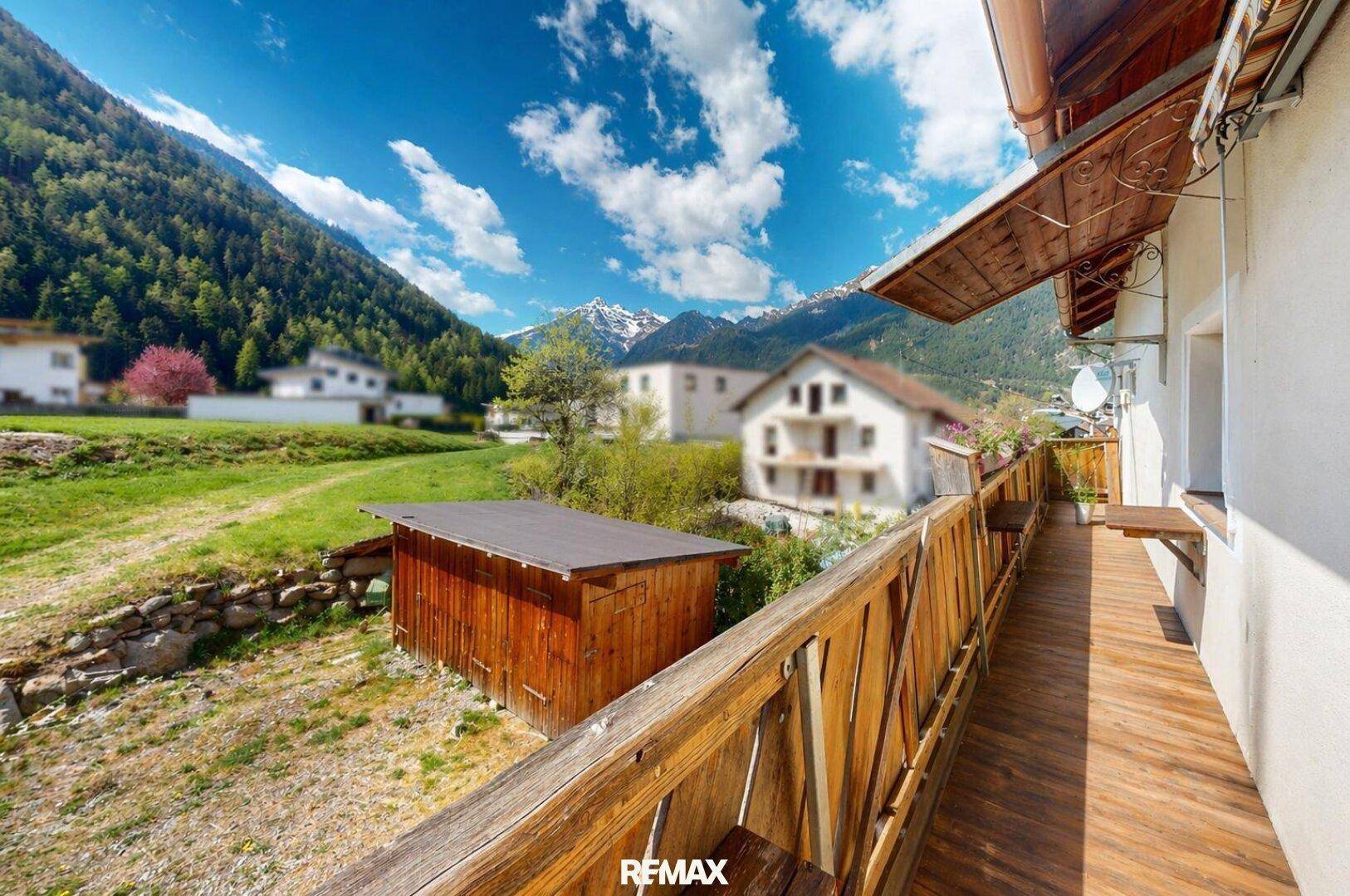 Langer Holzbalkon mit malerischem Blick auf die umliegenden Berge und das Tal.