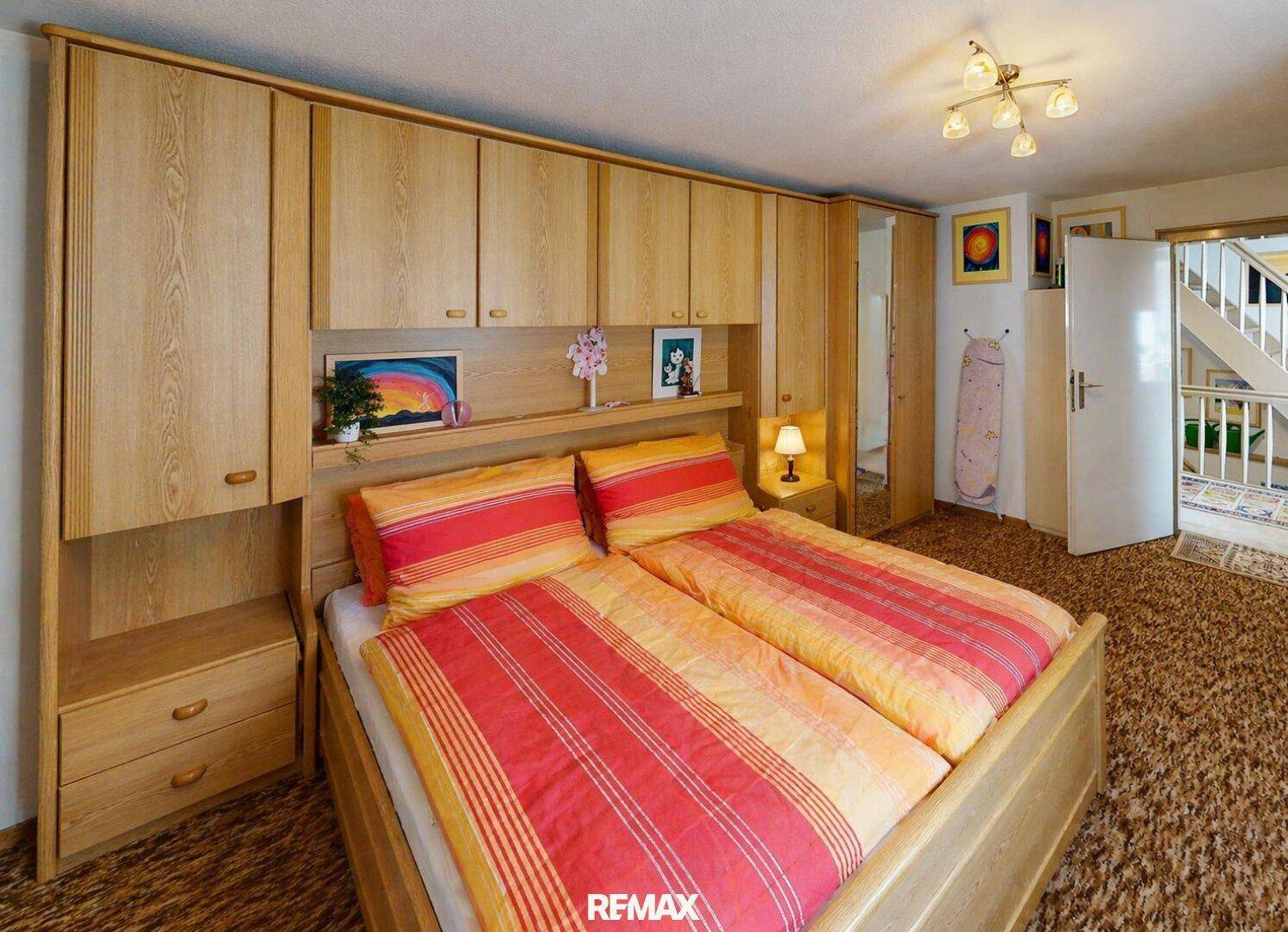 Schlafzimmer mit Doppelbett und integrierten Holzschränken, die viel Stauraum bieten.