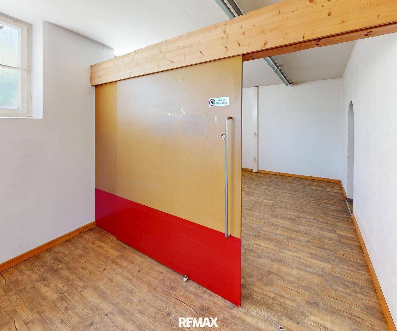 Große Schiebetür aus Holz und Metall in einem hellen Gewerberaum mit Holzboden und sichtbarem Holzbalken.