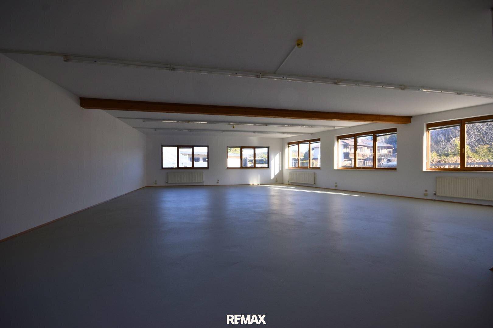 Großer, heller Gewerberaum mit vielen Fenstern, hohen Decken und sichtbaren Holzbalken.