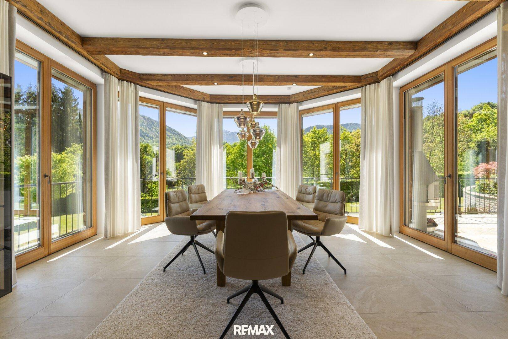 Eleganter Essbereich mit großem Holztisch, modernen Stühlen und Panoramafenstern mit Bergblick.