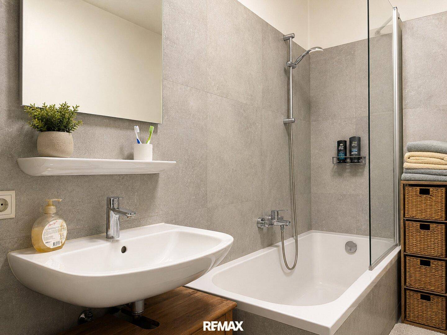Modernes Badezimmer mit Badewanne, Duschwand und Waschbecken auf Holzunterschrank.